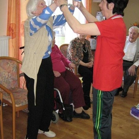 Ein Mitarbeiter tanzt mit einer alten Frau