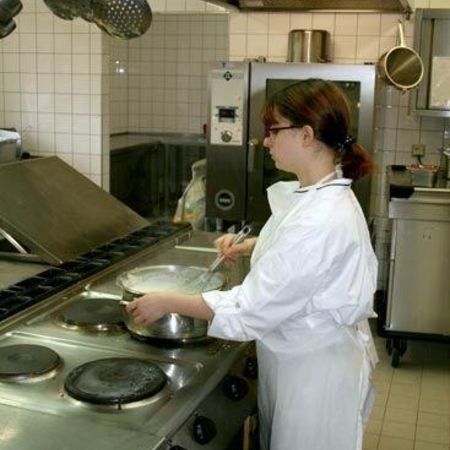 Eine Köchin steht vor dem Herd und bereitet etwas zu