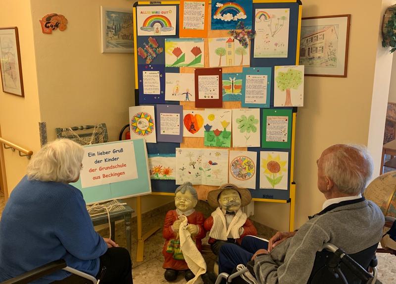 Zwei ältere Herrschaften schauen sich Bilder der Grundschule Beckingen an